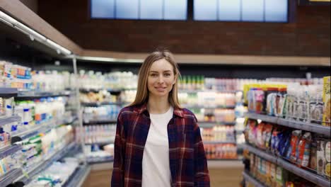 Portrait-woman-stands-in-front-of-the-camera-with-shopping-cart-in-supermarket