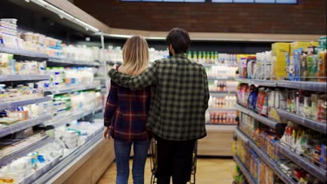 Couple-pushing-shopping-cart-in-supermarket,-rare-view
