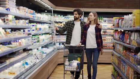 Couple-shopping-in-supermarket-with-cart,-front-view