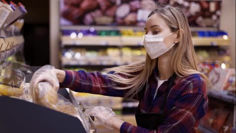 Female-staff-in-mask-working-at-bakery-section-of-supermarket