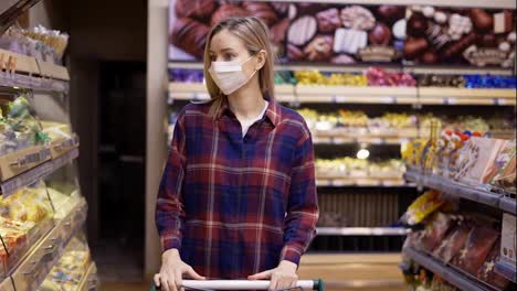 Young-woman-carries-a-cart-in-the-supermarket-during-the-quarantine-period-in-mask