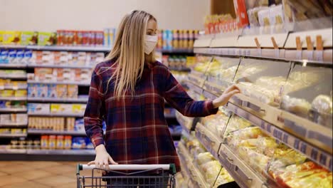 Young-woman-carries-a-cart-in-the-supermarket-during-the-quarantine-period,-taking-bread