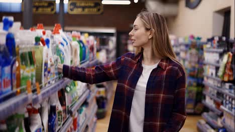 Woman-choosing-detergent-at-a-household-goods-in-the-store,-put-it-into-cart