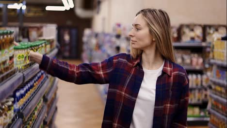 Woman-buys-food-at-supermarket-or-grocery-shop-with-shopping-cart