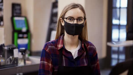 Portrait-of-a-woman-in-a-medical-mask-working-at-the-checkout-in-a-supermarket