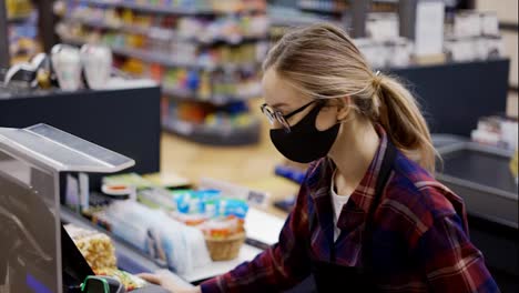 Female-cashier-in-a-protective-mask-talking-to-a-customer