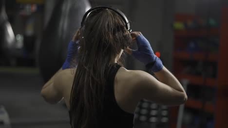 Rear-view-boxer-performing-punching-at-gym,-listen-music-with-headphones