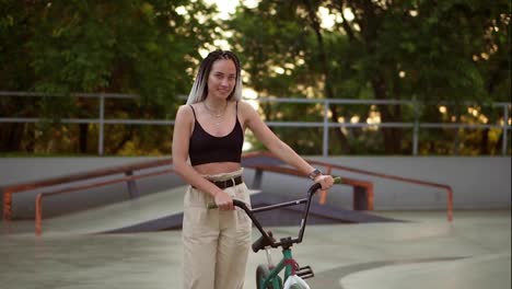 Chica-Atractiva-Y-Elegante-Con-Rastas-Camina-Con-Bicicleta-Bmx-En-Skatepark-En-Un-Parque-Recreativo.-Mujer-Joven-Y-Elegante-Andando-En-Bicicleta