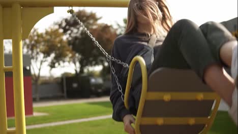 Long-haired-woman-swinging-on-a-swing-in-the-green-park,-happily-smiling