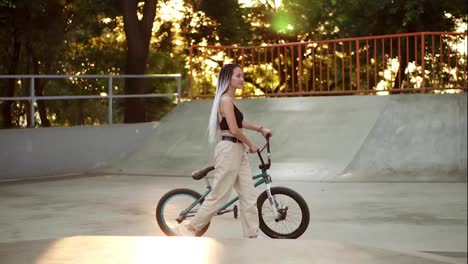 Chica-Atractiva-Y-Elegante-Con-Rastas-Camina-Con-Bicicleta-Bmx-En-Skatepark-En-Un-Parque-Recreativo.-Mujer-Joven-Y-Elegante-Andando-En-Bicicleta