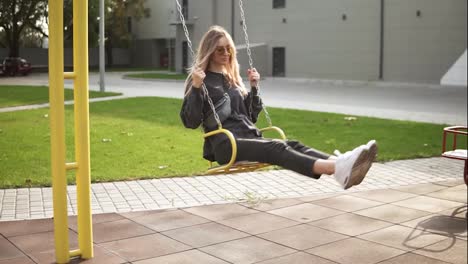 Long-haired-woman-swinging-on-a-swing-in-the-green-park-calmly