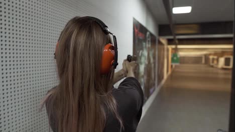 Long-haired-woman-in-protective-headphones-trainings-in-shooting-range