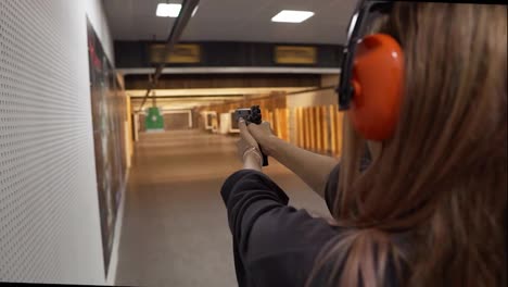 Long-haired-woman-in-protective-headphones-trainings-in-shooting-range,-targeting