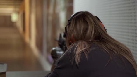 Woman-with-rifle-in-hands-at-shooting-range-with-target,-excited-and-surprised
