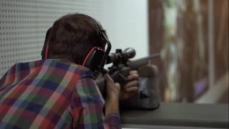 Close-up-of-a-man-shooting-use-rifle-at-shooting-range-in-headphones