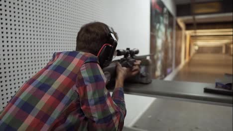 Rare-view-of-a-man-shooting-use-a-rifle-at-shooting-range-in-headphones