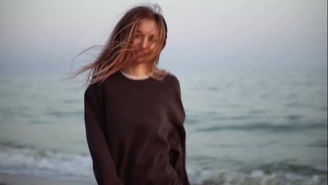 Long-haired-woman-runs-happily-along-the-autumn-seashore,-looking-to-the-camera