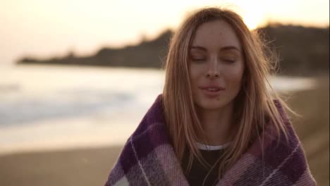 Portrait-of-a-girl-wrapped-in-a-blanket-on-the-beach-in-autumn