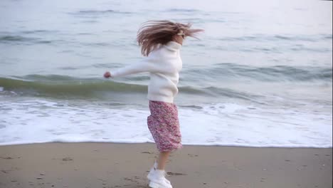 A-stylish-woman-whirling-happily-on-the-autumn-seashore-spreading-hands