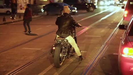 Rare-view-of-motorcyclist-drives-a-bike-in-the-city,-waiting-traffic-light-at-night