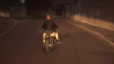 Rare-view-of-a-man-riding-on-a-motorcycle-on-a-turn-clings-to-the-asphalt,-sparks-fly-at-night
