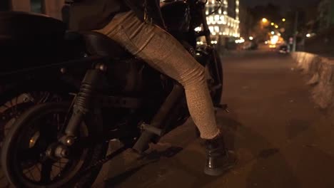 Low-angle-view-of-a-brutal-rider-sitting-on-motocycle-on-the-city-night-street