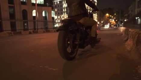 Stylish-rider-starts-on-motobike,-making-wide-turn-on-the-street-road-at-night