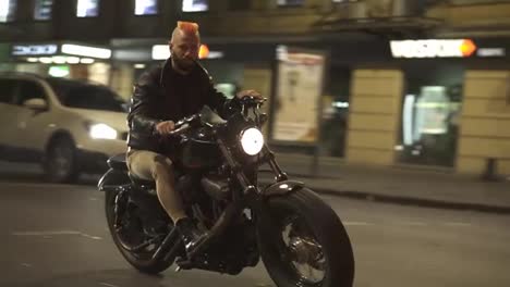 Stylish,-brutal-motorcyclist-drives-a-bike-in-the-city-with-bright-headlight-by-street-road