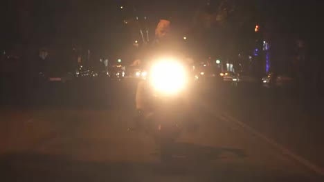 Stylish,-brutal-motorcyclist-drives-a-bike-in-the-city-with-bright-headlight-by-street-road-in-fog