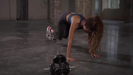 Young-sporty-stylish-woman-train-her-body-workout-her-muscles-indoor-at-empty-studio.-Athletic-beautiful-styylish-woman-with-long-dreadlocks-does-running-plank-exercise