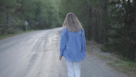 Mujer-Caminando-Sobre-Camino-Pavimentado-En-El-Bosque,-Vista-Trasera