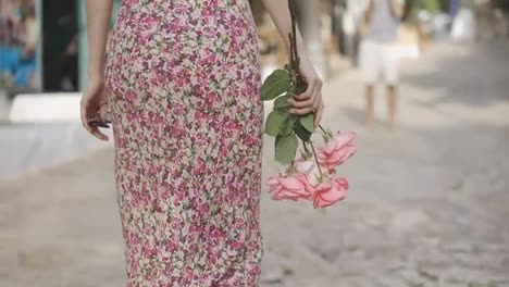 Cropped-view-of-a-girl-walking-by-the-street-with-pink-roses