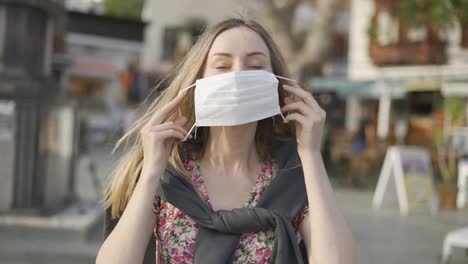Blonde-woman-putting-on-medical-mask-on-crowdy-street