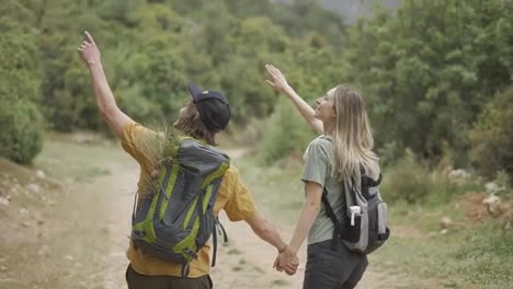 A-happy-couple-backpackers-walking-by-forest's-path-and-holding-hands