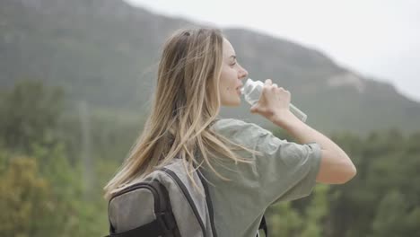 A-woman-drinks-water-from-a-bottle-during-hiking