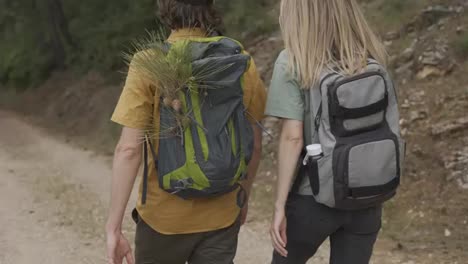 Unrecognizable-couple-backpackers-walking-by-forest's-rocky-path