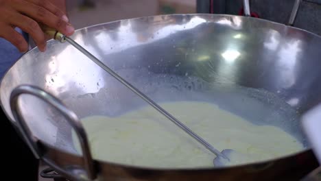 close-up-scene-of-A2-on-a-pan-stirring-milk-with-a-whisk-and-adding-saffron-ingredients-to-make-a-quality-product