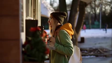 Woman-choosing-goods-in-street-kiosk-on-winter-walk.-Smiling-to-the-camera