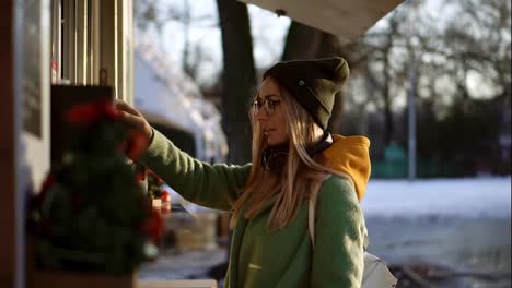 Woman-choosing-goods-in-street-kiosk-on-winter-walk,-think-for-order