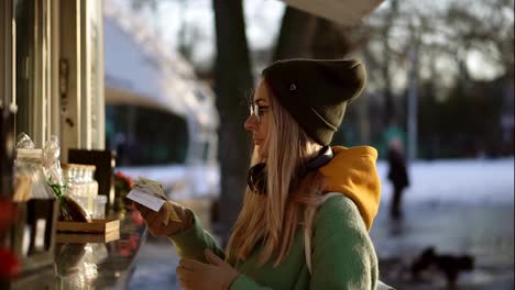 Frau-Mit-Hut,-Die-Im-Winter-Geld-Vom-Straßencafé-Kiosk-Nimmt
