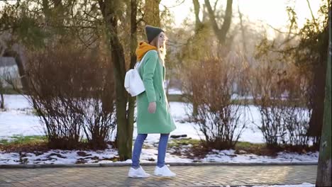 Woman-walk-freerly-in-winter-park-in-green-winter-coat