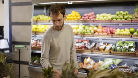 Man-takes-a-fresh-fruits-from-the-food-shelf.-Shopper-choosing-persimmon-at-grocery-store