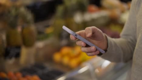 Close-up-of-a-man-using-mobile-smart-phone-at-grocery-store