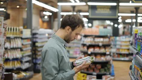 Young-man-is-selecting-household-chemicals-in-supermarket.-He-comparing-trademarks,-prices,-reading-labels-and-ingredients.-Close-up