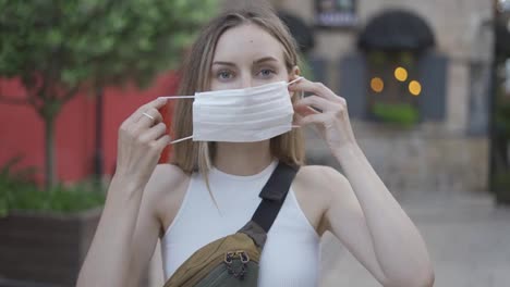 Woman-putting-on-medical-mask-for-coronavirus-protection-outdoors