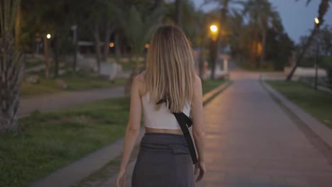 Blonde-young-female-traveler-walking-by-evening-city