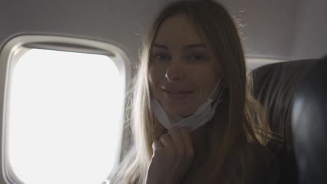 Portrait-of-woman-taking-off-mask-on-plane-looking-to-the-camera