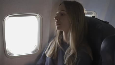Blonde-Frau-Setzt-Im-Flugzeug-Eine-Schutzmaske-Auf