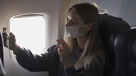 Young-woman-wearing-face-mask,-taking-selfie-on-board