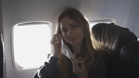 Blonde-woman-putting-on-mask-on-plane-and-smiling